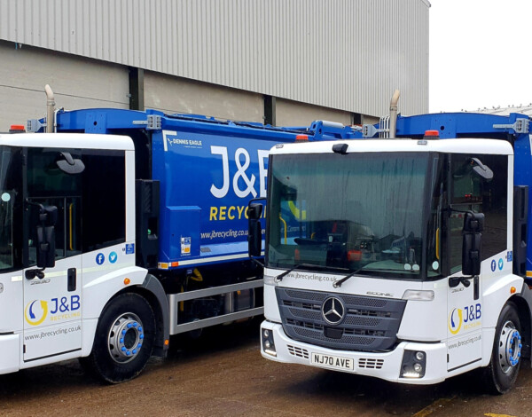 Photo of blue and white recycling trucks with J&B recycling logo, in the yard at the recycling plant