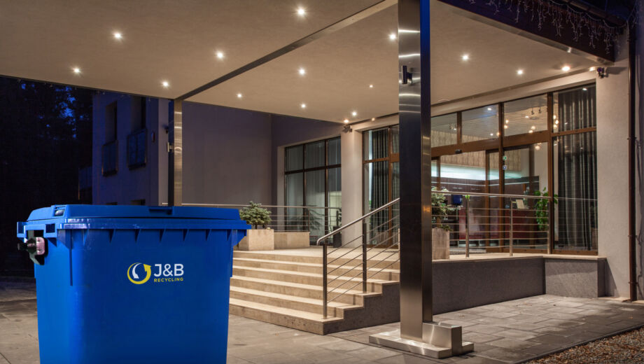Large wheelie bin outside hotel. Blue recycling bin with J&B recycling logo